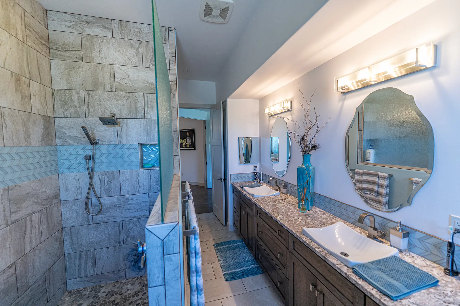 Modern bathroom designed by a custom home builder in Prescott with dual vanities and walk-in shower